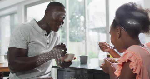 African American father and daughter sharing breakfast and laughing at modern kitchen island