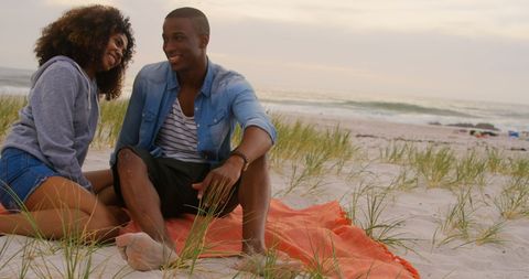 Happy Couple Relaxing on Sandy Beach at Sunset