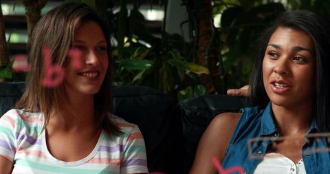 Two women chatting on couch with marker board and plants, casual lounge collaboration