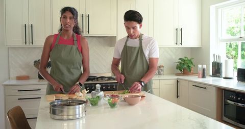 African couple preparing meal in modern kitchen chopping vegetables on marble island