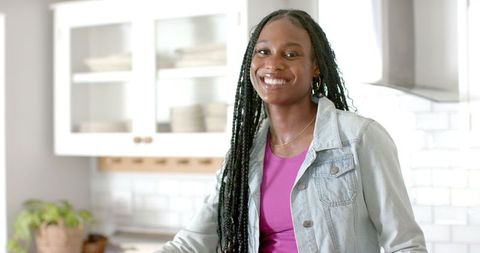 Smiling Woman in Kitchen Preparing Groceries with Natural Light