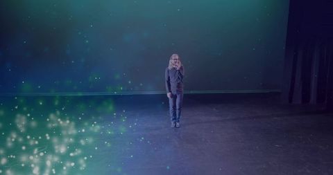 Male Performer Singing with Microphone on Theater Stage Under Spotlight