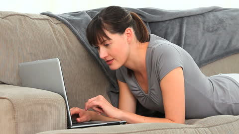 Woman Relaxing on Couch Using Laptop for Communication