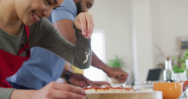 Smiling Woman Adding Cheese to Homemade Pizza in Kitchen - Download Free Stock Images Pikwizard.com