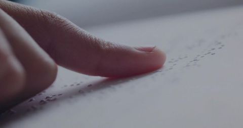 Fingertip gently tracing braille text, emphasizes accessibility