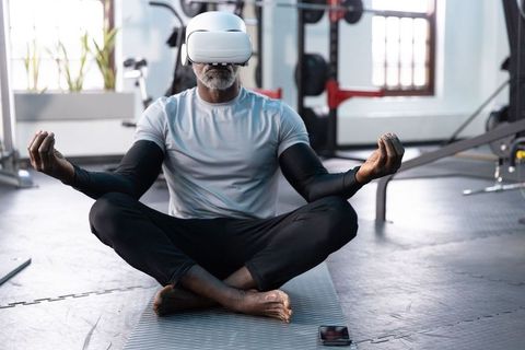 Mature african american man meditating with vr headset in gym studio for mindful fitness