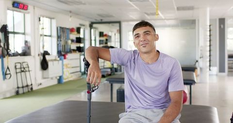 Man in Rehabilitation Center Sitting with Crutches Smiling