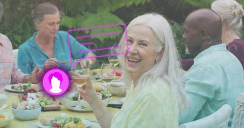 Senior woman holding wine glass smiling at backyard dinner with purple ar social overlay
