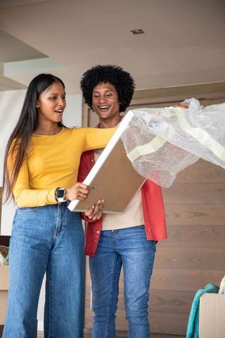 Diverse couple unpacking picture frame in new home