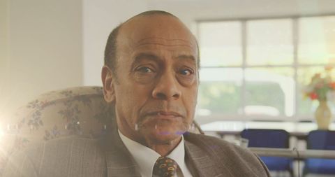 Serious Senior Man Relaxing in Chair with Sunbeam Glare