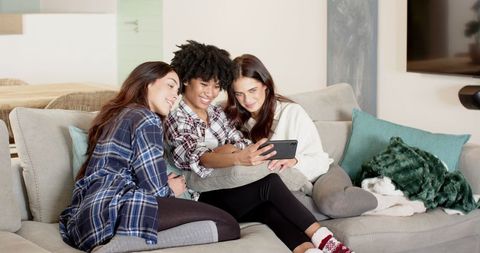 Diverse Friends Relaxing on Sofa Sharing Tablet at Home