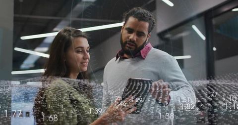 Tech team analyzing live data on tablet with holographic numeric overlay in modern office