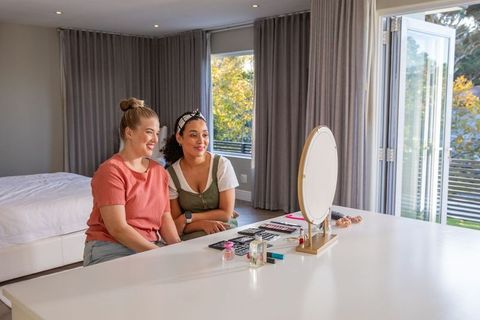 Friends enjoy makeup session together in stylish bedroom interior