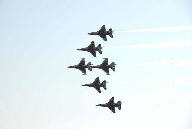 Fighter jets from the USAF Thunderbirds demonstrate precise flying skills as they soar in a tight formation against a clear sky during the World Space Expo at Kennedy Space Center in Florida. This event commemorates humanity's milestones in space exploration and features various aircraft including F-18 Super Hornets and F-22 Raptors. Suited for use in topics about airshows, military aviation, aerospace events, and commemorations involving space exploration history and anniversaries.