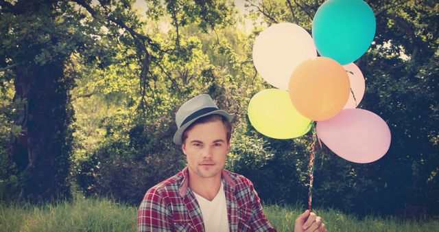 Young Man Holding Colorful Balloons Outdoors - Download Free Stock Images Pikwizard.com