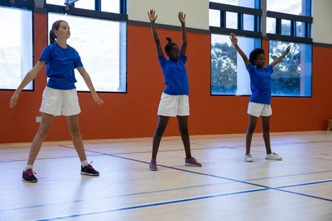 Diverse group of female students warming up in school gym