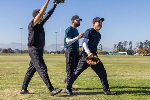 Sunlit baseball teammates walking and celebrating on grassy field