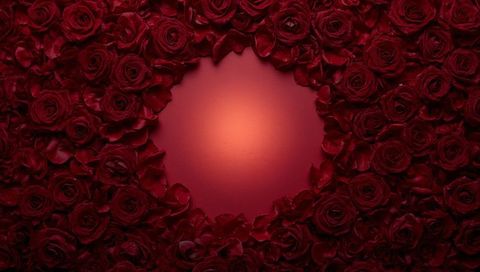 Framing heart-shaped negative space with deep red roses and warm glowing center
