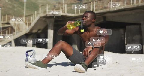 Black man cooling down on beach after workout drinking from green bottle with kettlebell