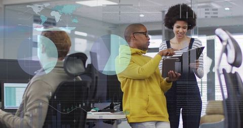 Collaborating professionals reviewing tablet and dashboards in modern open-plan office