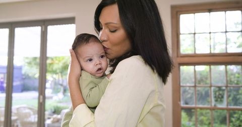 Mother Gently Holding and Kissing Infant at Home