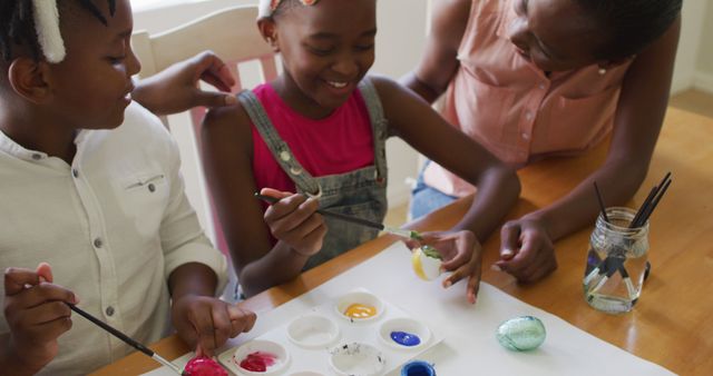 Family members painting Easter eggs at home, showcasing joy and bonding. This can be used for holiday promotions, family activity guides, or creative workshops. Ideal for content around Easter celebrations, crafts, and family activities.