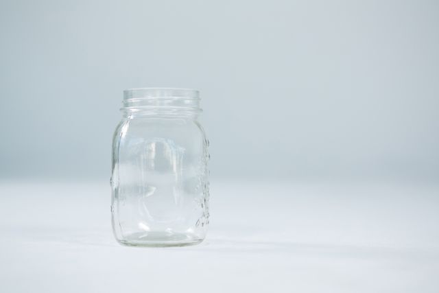Close-up of empty glass jar on white background
