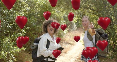 Friends hiking on forest trail pointing and discovering floating red hearts overlay