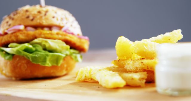 A close-up view of a delicious burger accompanied by crispy French fries and a small cup of dipping sauce. The focus on the texture of the food items makes this a tempting display for those craving a classic fast-food meal.
