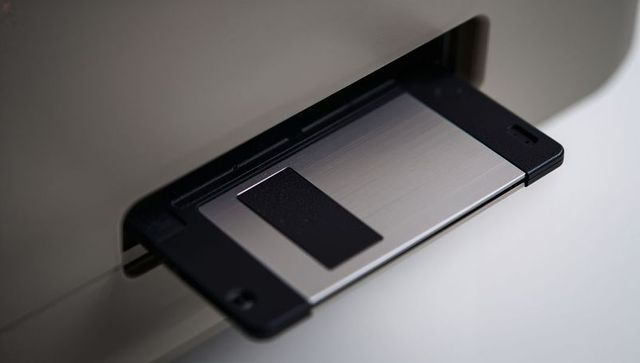 3.5-inch floppy disk sliding into drive slot closeup - retro computer storage detail