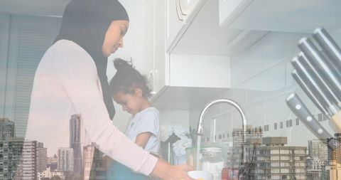 Asian Mother and Daughter Enjoying Time in Kitchen Over Cityscape