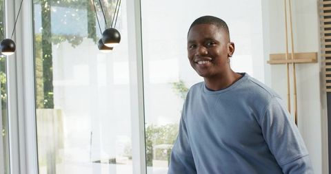 African american man smiling and leaning by glass doors in modern minimalist interior