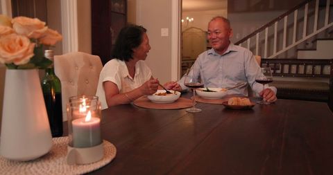 Senior Couple Enjoying Cozy Dinner Evening with Wine at Home