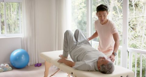 Physiotherapist Assisting Senior In Physical Therapy Session