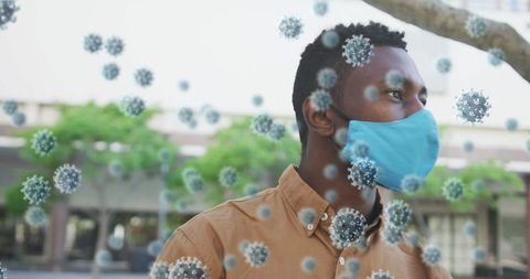 Man wearing face mask surrounded by covid-19 virus illustrations