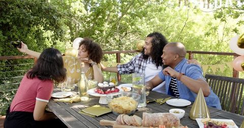 Joyful friends celebrating birthday with selfies outdoors