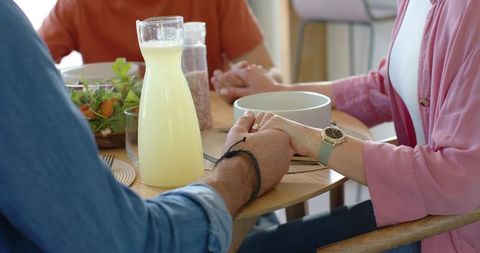 Couple holding hands at cozy breakfast table with carafe of fresh juice