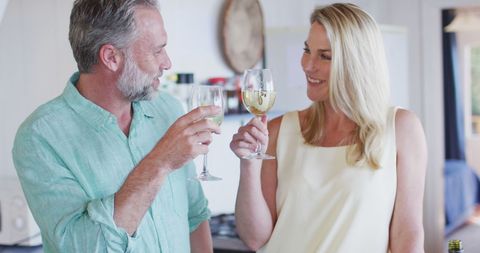 Happy Mature Couple Toasting Wine in Home Kitchen