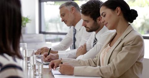 Diverse business team taking notes during board meeting, focused corporate collaboration