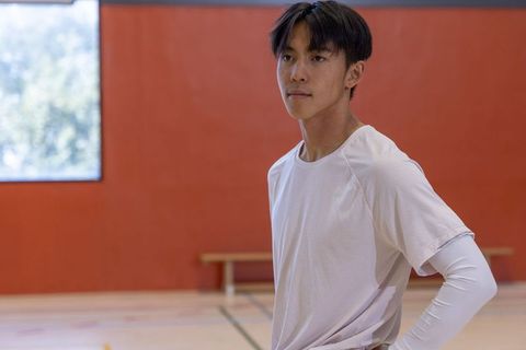 Young asian athlete standing in indoor gym wearing white training top and long sleeve