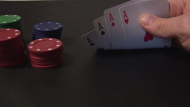 Video depicts a winning poker hand with four aces being held, accompanied by stacks of poker chips on a blackjack table surface. Ideal for content related to gambling, strategy, casino games, betting, or card games.