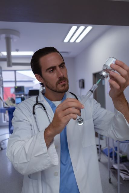 This image shows a male doctor drawing medicine into a syringe in a hospital. Ideal for use in healthcare-related content, medical articles, websites of hospitals and clinics, pharmaceutical advertisements, and educational materials for medical training.