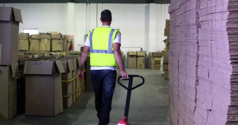 Worker using pallet jack in warehouse storage facility