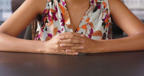 Businesswoman gesturing confidently in floral blouse at office desk