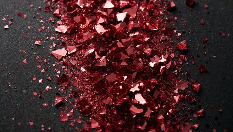Crimson reflective foil shards and glitter band on dark matte surface
