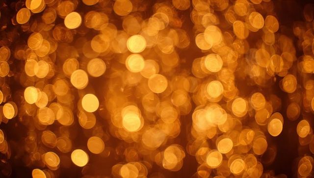 Glowing gold bokeh lights filling dark backdrop with warm festive sparkle and amber orbs