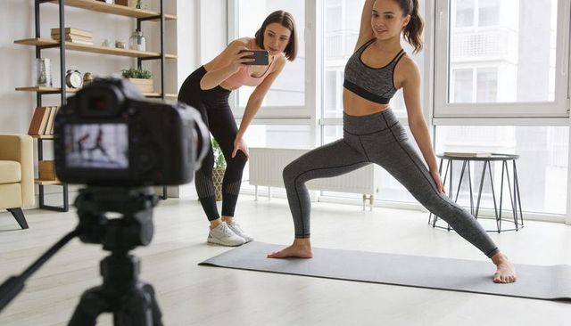 Home Fitness Instructor Filming Lunge Workout with Assistant and DSLR for Online Content