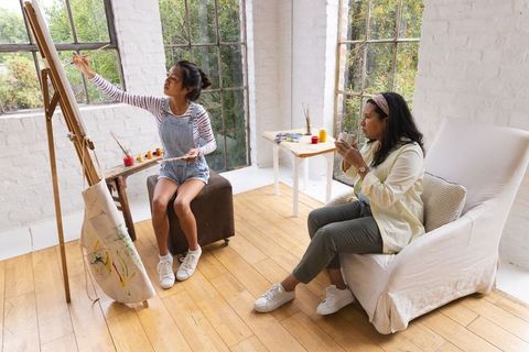 Creative asian teen painting with mother in sunlit art studio