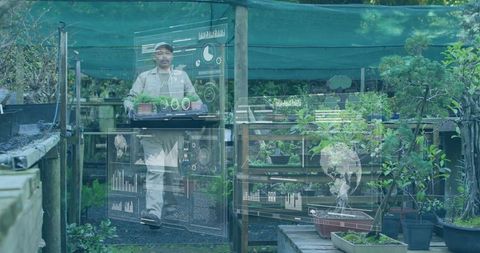 Nursery worker carrying seedling tray while viewing augmented reality data overlays