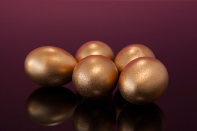 Close-up of golden Easter eggs on colored background